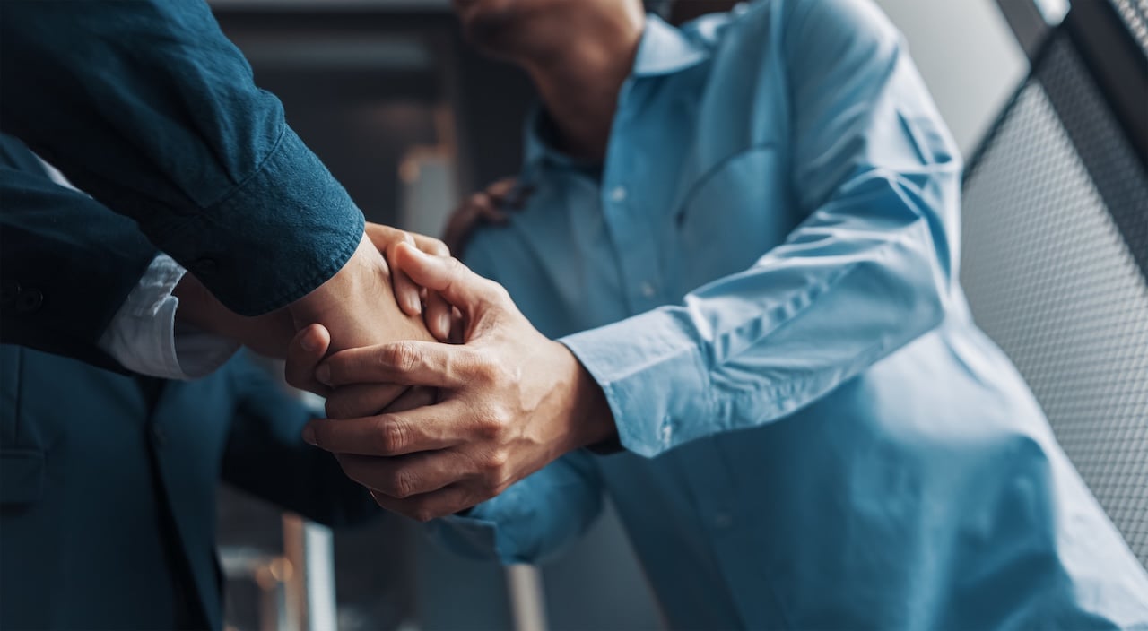 Two business professionals shaking hands in an office setting, symbolizing a successful partnership or referral agreement in the restoration industry.