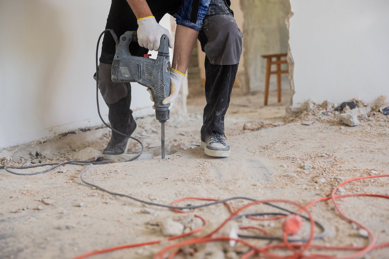 Worker demoing a concrete floor during restoration project. 