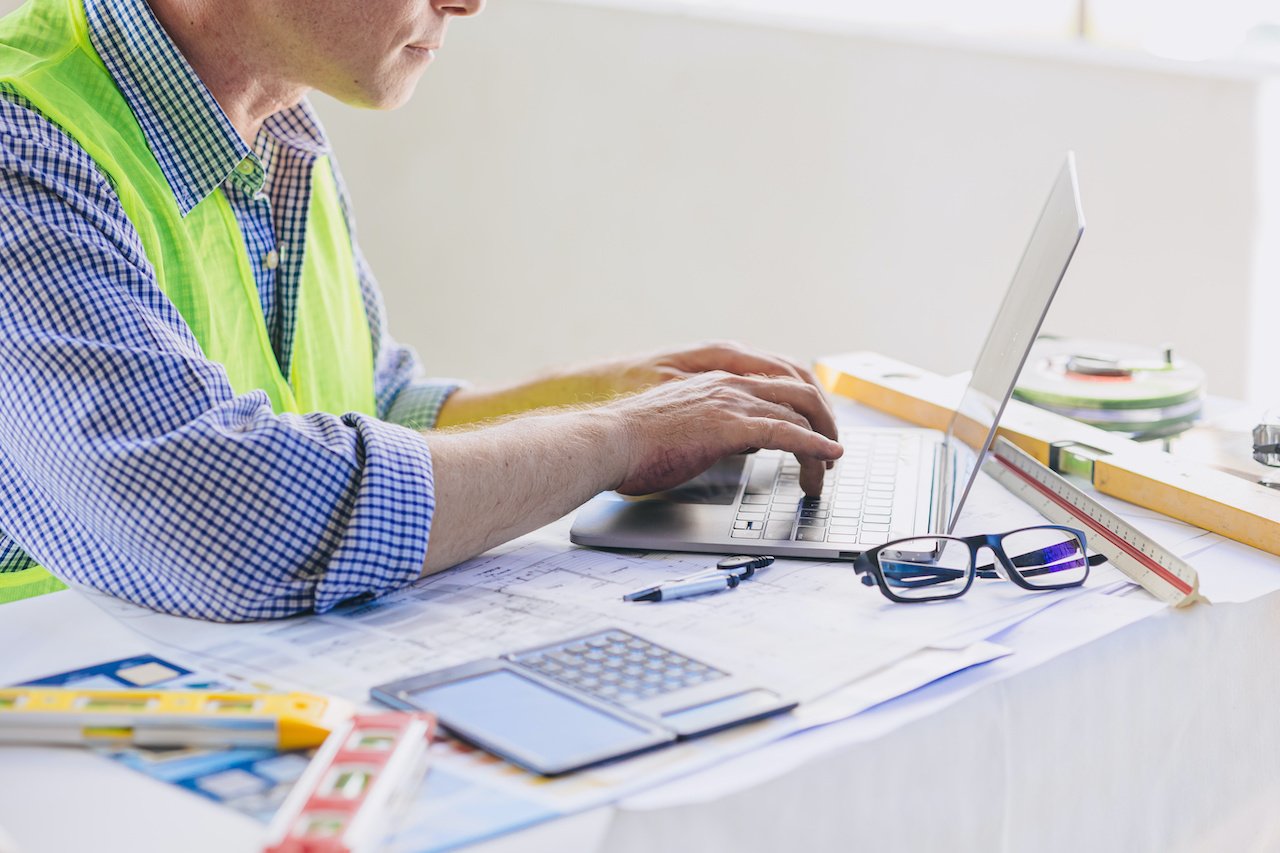 construction-engineer-builder-working-at-desk-typing-on-laptop