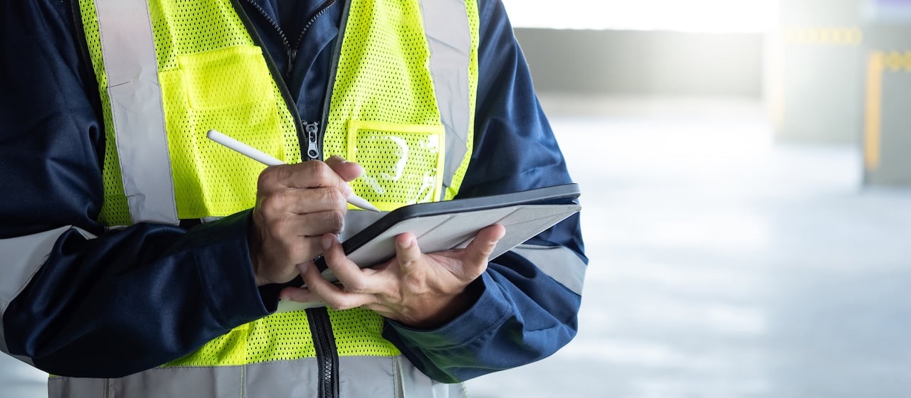 Restoration technician using a tablet checklist on a job site to track tasks.