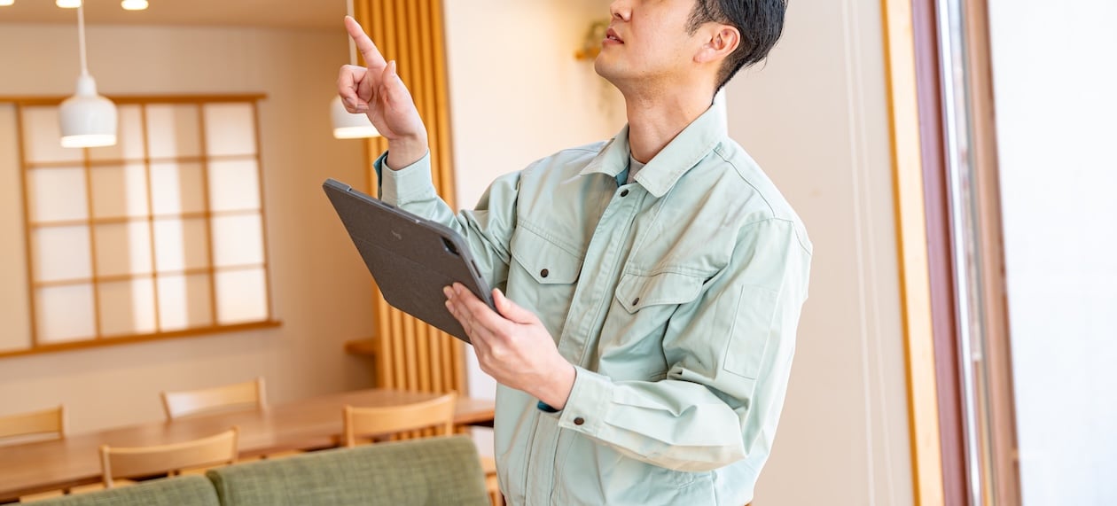 Contractor in work clothes checking a tablet to confirm job information, representing digital documentation and scheduling in restoration workflows.