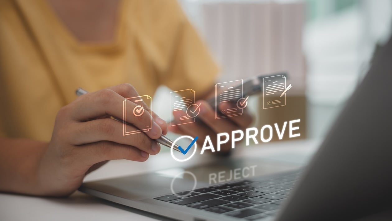 Digital approval workflow displayed on laptop screen as office employee reviews submitted documents and pending verification steps during a delayed business approval process.