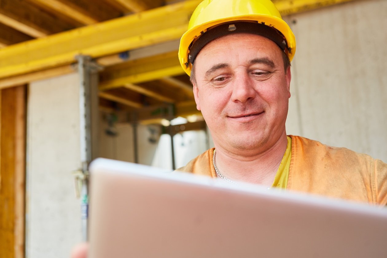 Foreman in a hard hat uses a tablet during construction planning at a building site. 