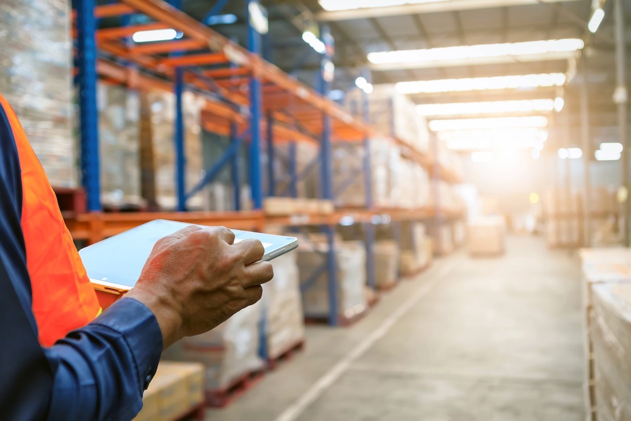 Technician reviewing job and inventory information on a tablet in a warehouse.