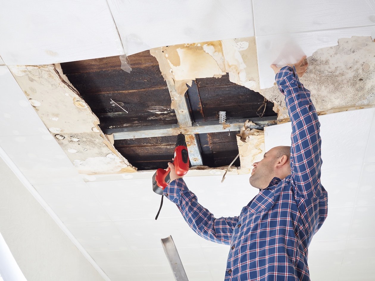 Restoration contractor repairing a collapsed ceiling in a damaged home.