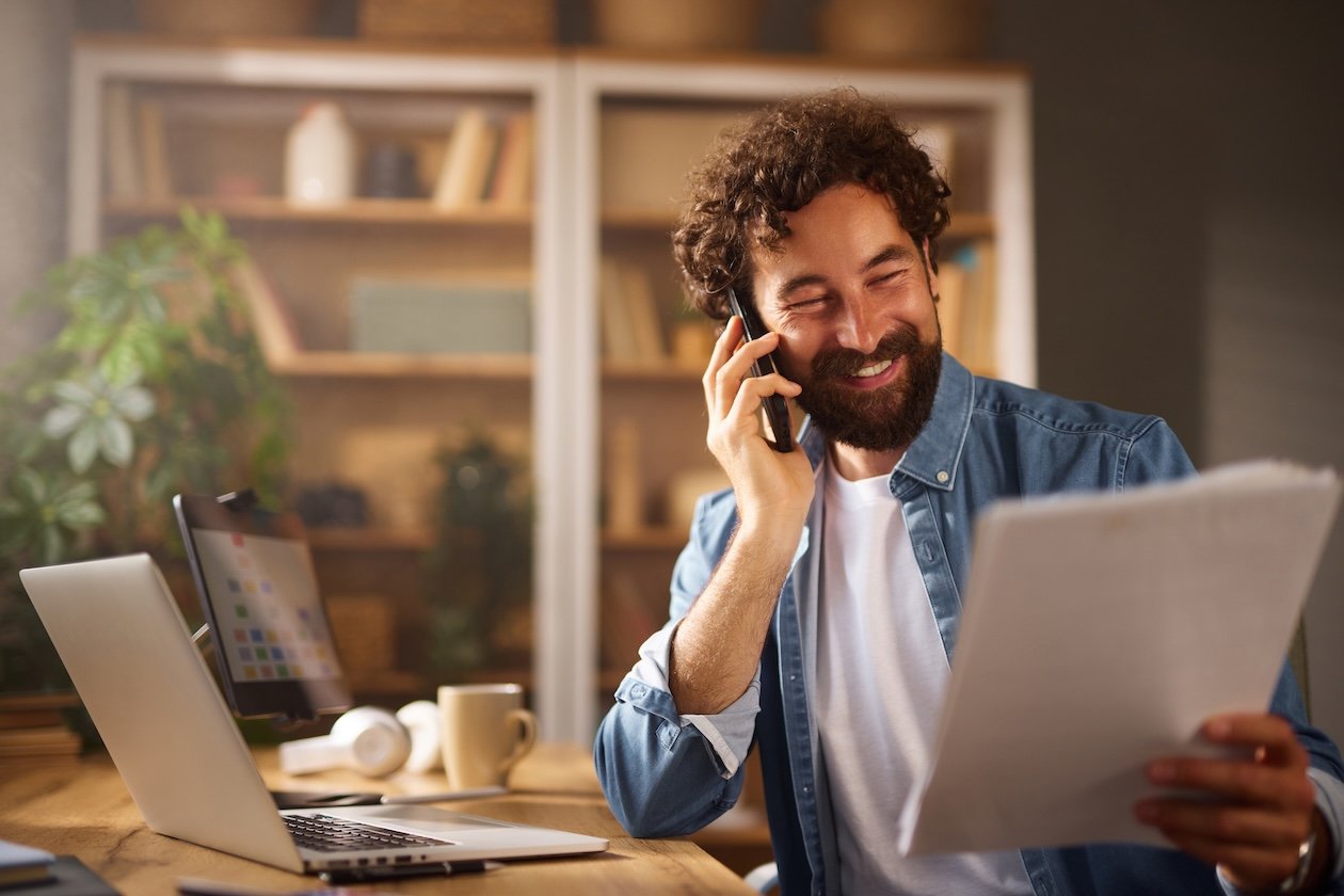 Restoration manager reviewing paperwork while on a phone call in an organized office, reflecting manual job coordination despite a well-structured workspace.