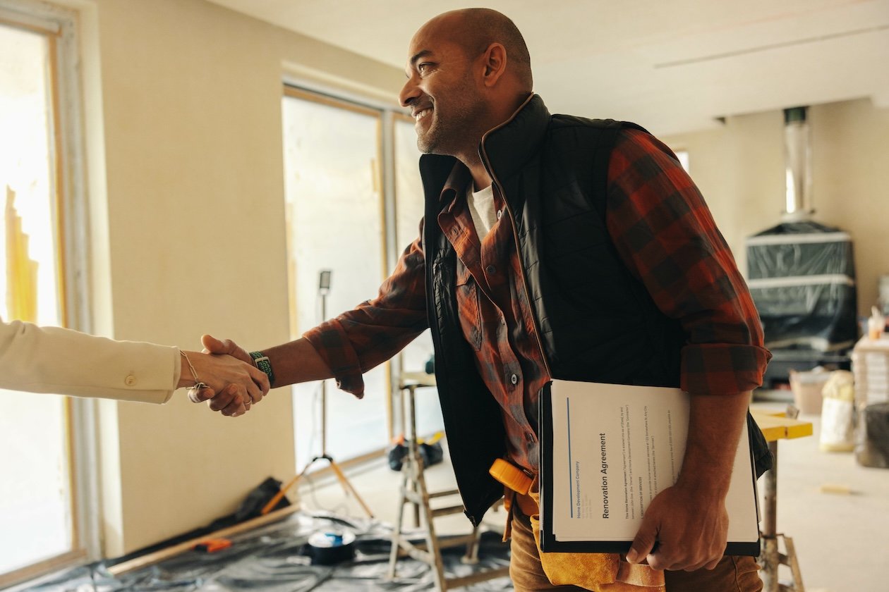 Professional contractor shaking hands with a homeowner while working on an interior restoration project.