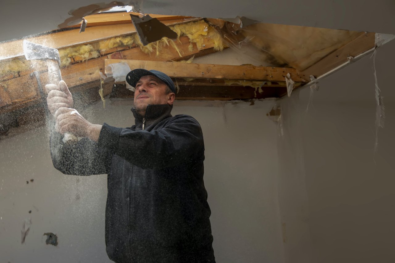 Worker preparing damage ceiling for restoration.