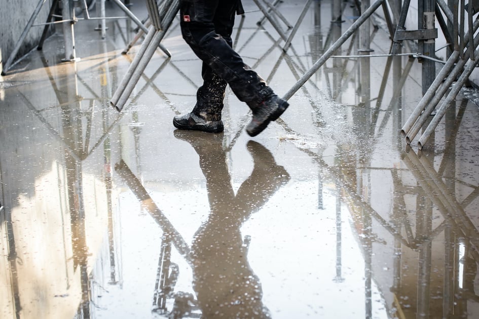 Restoration worker walking on wet concrete.