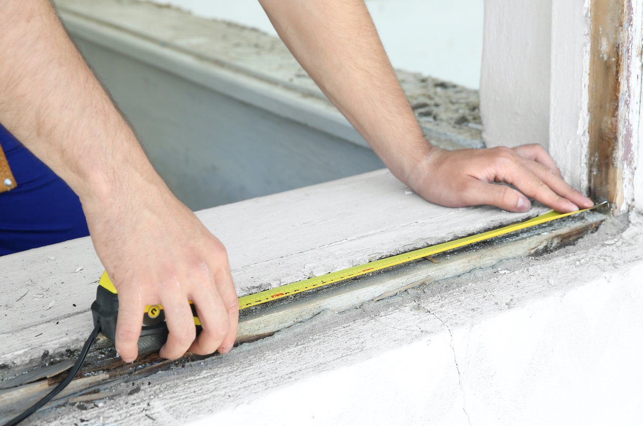 Restoration worker measuring a damaged window. 