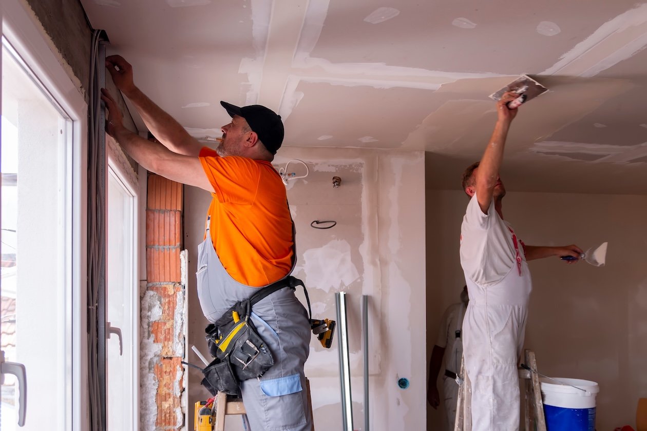 Two restoration professionals working on a ceiling.
